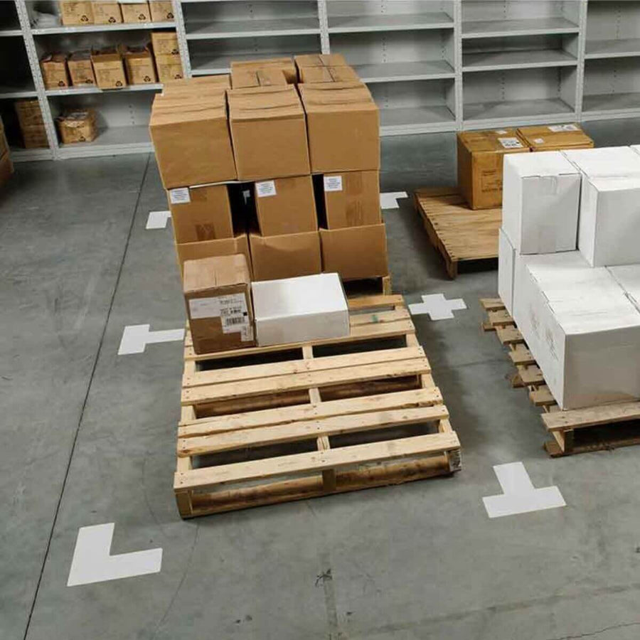 Warehouse pallet area marked with white floor tape corners, used for 5S visual management and storage organization